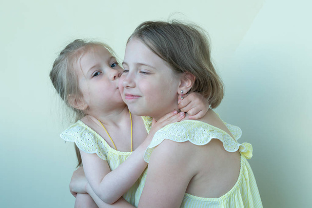 portrait of two little girls in the studio, standing in yellow dresses - Photo, Image