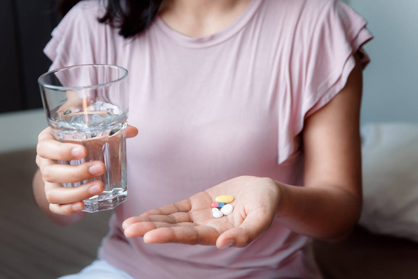 Close-Up mão mulher está segurando vidro de água enquanto tomando pílulas, cuidados de saúde e medicina conceito
. - Foto, Imagem