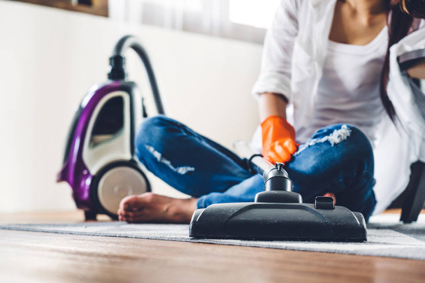 junge Frau in Schutzhandschuhen putzt Haus mit Staubsauger - Foto, Bild
