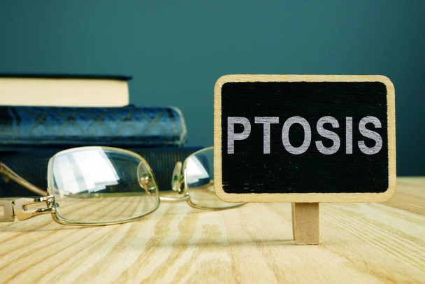 Ptosis disease. Eye glasses and book on desk. - Foto, Bild