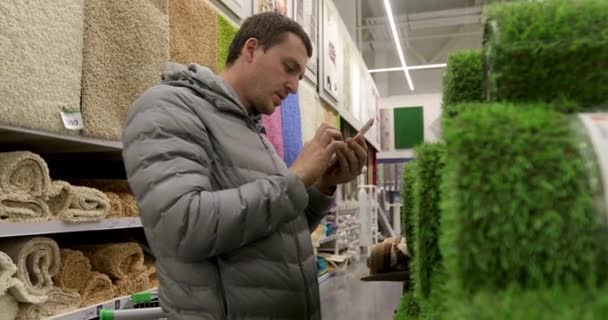 Mann benutzt Smartphone in Verbrauchermarkt - Filmmaterial, Video