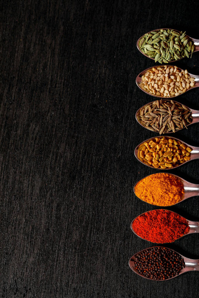 spices in spoons on black background - Foto, imagen