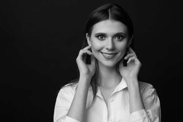 Black and white portrait of a beautiful woman in a white shirt on a black background - Фото, зображення