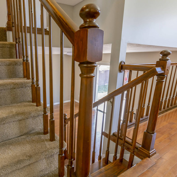 Escalera cuadrada alfombrada con pasamanos marrón dentro de una casa ingenio
 - Foto, imagen