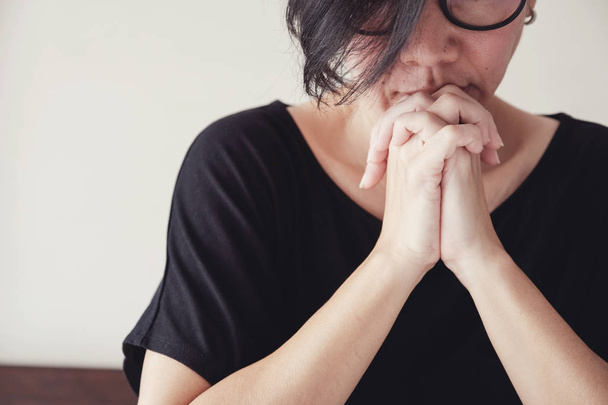 Asian middle aged woman wear glasses praying with hands together - Foto, Imagen