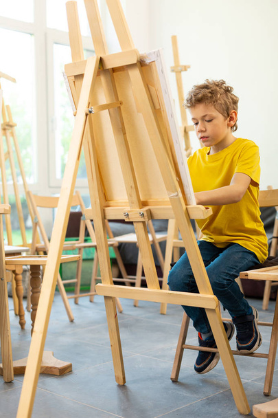 Schoolboy feeling joyful while painting in art school - Фото, зображення