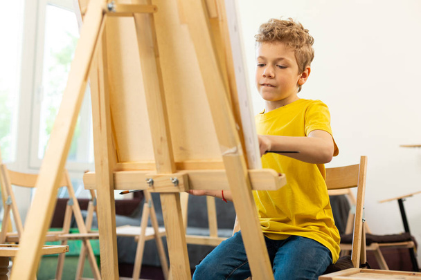 Talented boy feeling good while painting in art school - Fotó, kép
