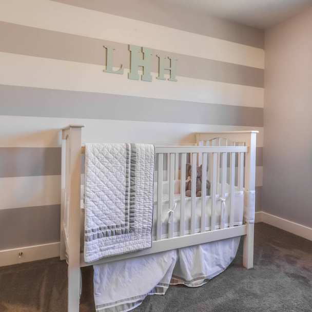 Square frame Interior of a nursery with white crib and monogram letters on the striped wall - Photo, Image