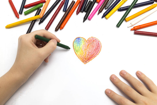 Levá ruka při kreslení tvaru srdce barevnými pastelky - Fotografie, Obrázek