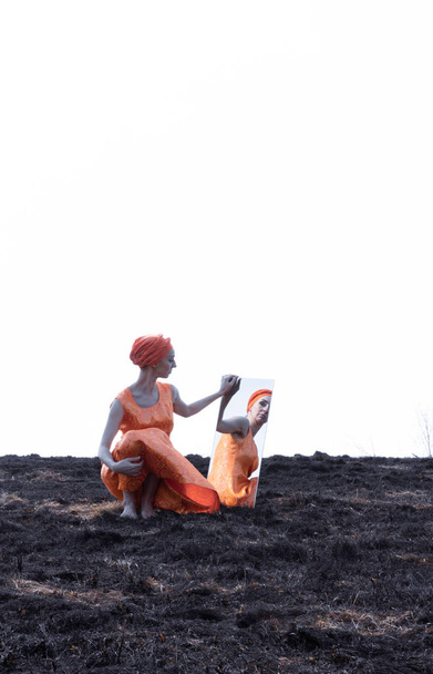 Woman in Eastern Clothes on Burnt Ground with Mirror - Foto, imagen