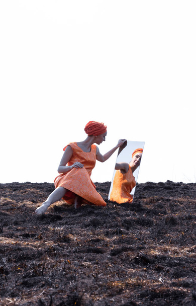 Woman in Eastern Clothes on Burnt Ground with Mirror - Фото, зображення