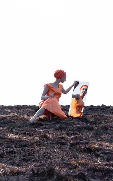 Woman in Eastern Clothes on Burnt Ground with Mirror - 写真・画像