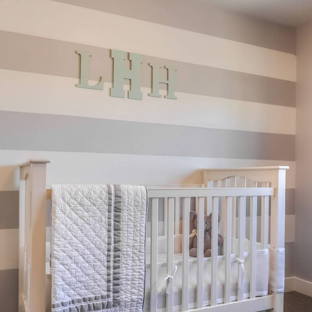 Square Interior of a nursery with white crib and monogram letters on the striped wall - Photo, Image