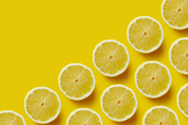 Fresh sliced lemon on yellow background. - Foto, afbeelding