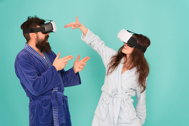 Hands up. Stand and deliver. VR technology and future. VR communication. Exciting impressions. Couple in bathrobes wear VR glasses. Gaming and entertainment. Man and woman explore VR at home - Foto, imagen