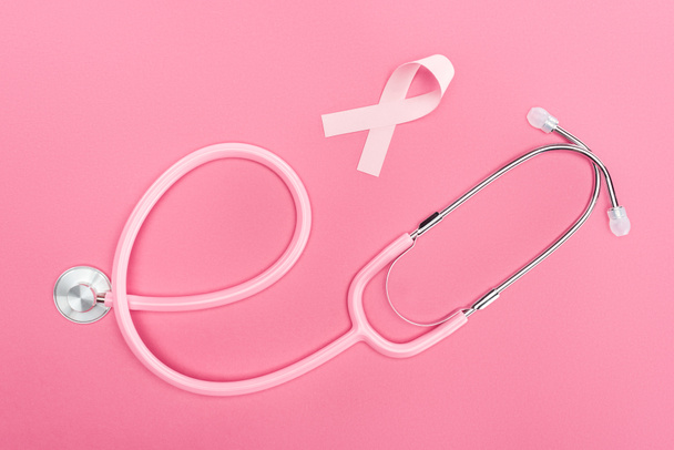 top view of stethoscope and pink breast cancer sign on pink background - Foto, immagini