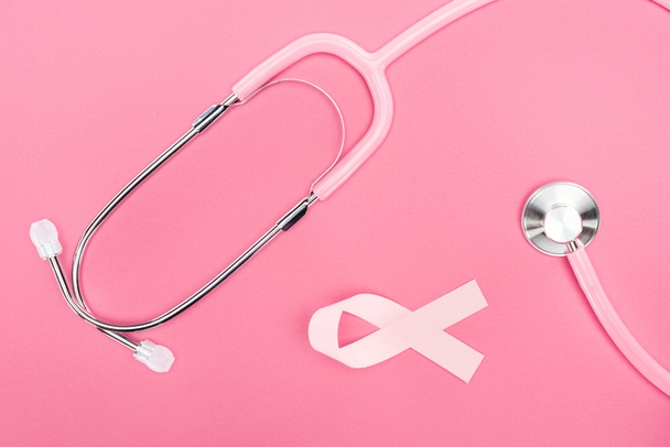 top view of stethoscope and pink breast cancer ribbon on pink background - 写真・画像