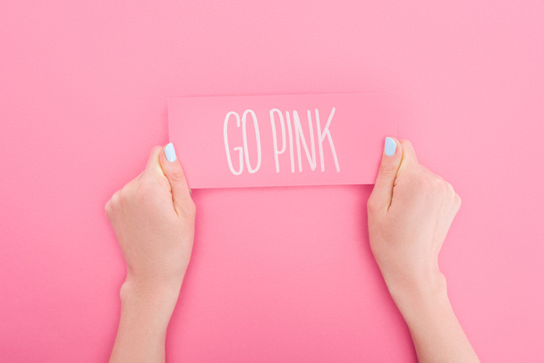 partial view of woman holding pink card with go pink lettering on pink background - Photo, Image