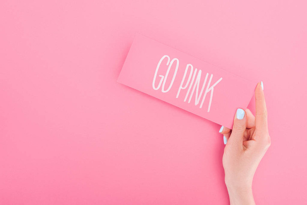 ピンクの背景に行くピンクの文字でカードを保持している女性の部分的なビュー - 写真・画像