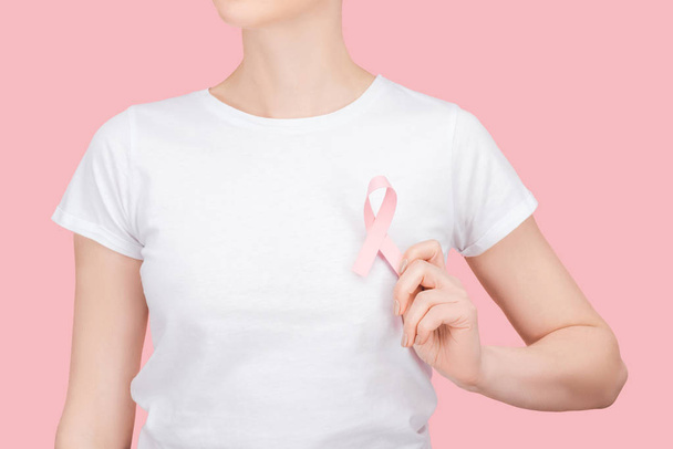 partial view of woman in white t-shirt with pink breast cancer sign isolated on pink - Foto, Bild