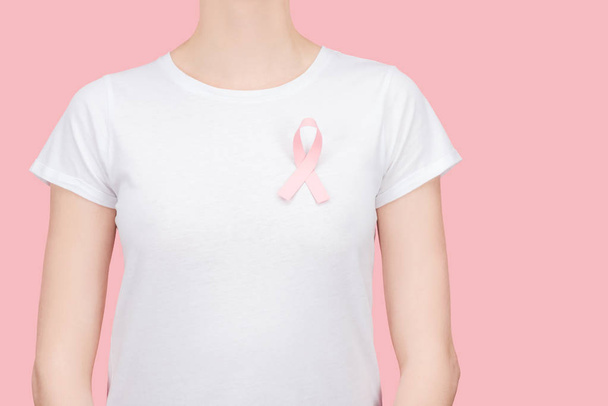 vista recortada de la mujer en camiseta blanca con signo de cáncer de mama rosa aislado en rosa
 - Foto, Imagen