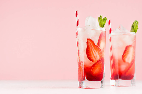 Juicy strawberry lemonades with ripe red fruit, ice cubes, straw, green mint on elegant pink pastel color background, copy space. - 写真・画像