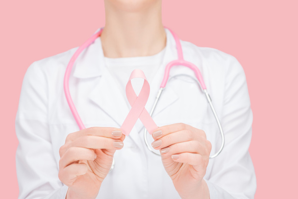 ピンクの乳癌の徴候を保持する白いコートの医師の選択的な焦点はピンクで隔離された - 写真・画像