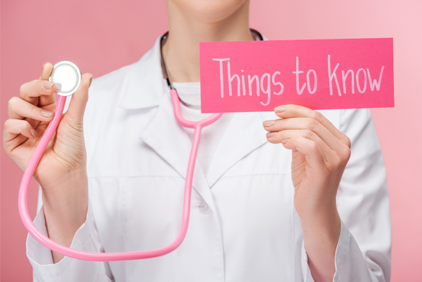 visão parcial do médico em casaco branco e estetoscópio cartão de retenção com coisas para saber lettering isolado em rosa
 - Foto, Imagem