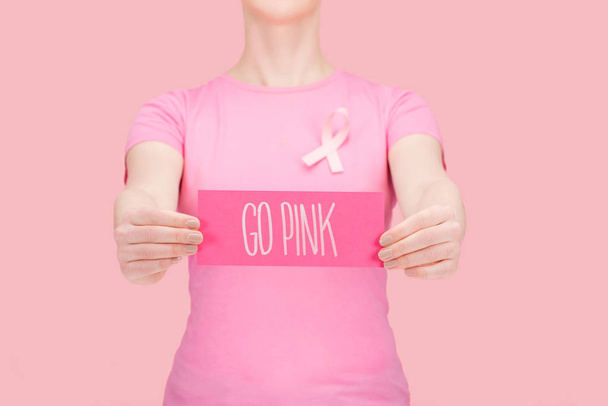 cropped view of woman in pink t-shirt pointing with finger at silk breast cancer sing isolated on pink - Фото, изображение