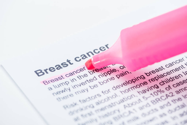στενή όψη της εφημερίδας εκτύπωσης με το άρθρο του καρκίνου του μαστού και ροζ δείκτη σε λευκό φόντο - Φωτογραφία, εικόνα