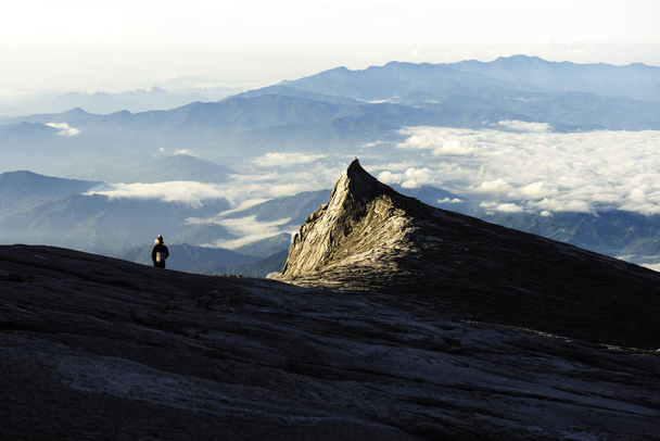 Trekker staande op Kinabalu Mountain met South Peak en Mountain - Foto, afbeelding