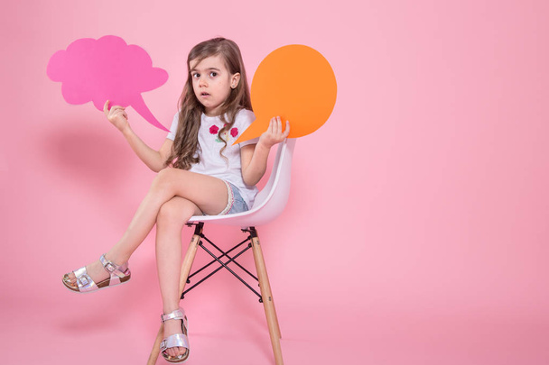 Cute little girl with an icon of a speech on a pink background - Foto, Imagen