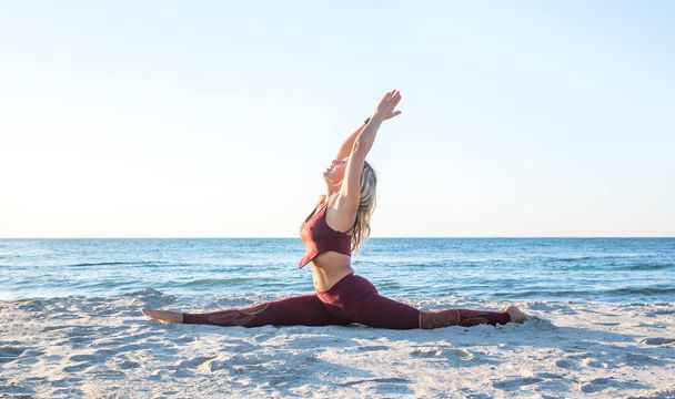 Kaukasische gezonde volwassen vrouw met mooi lichaam doen yoga bij zonsopgang op het strand, yoga poses - Foto, afbeelding
