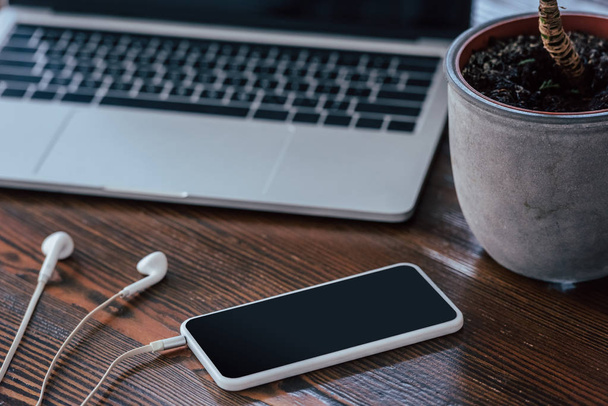 smartphone s prázdnou obrazovkou, sluchátkách a laptopy na dřevěném stole - Fotografie, Obrázek