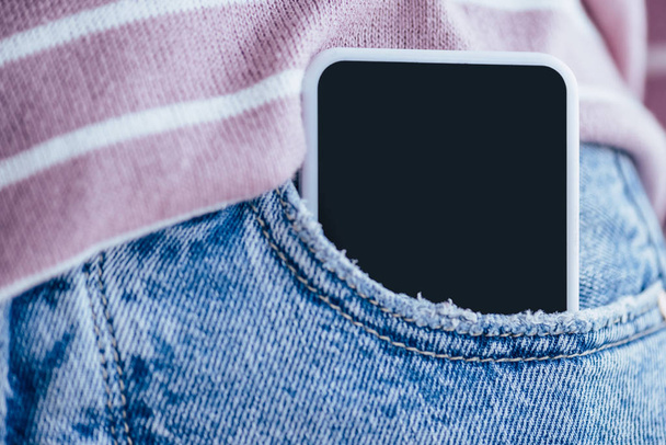 bijgesneden beeld van de man in denim jeans met smartphone in zak - Foto, afbeelding