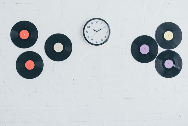 vinyl discs and round clock on white brick wall  - Fotografie, Obrázek