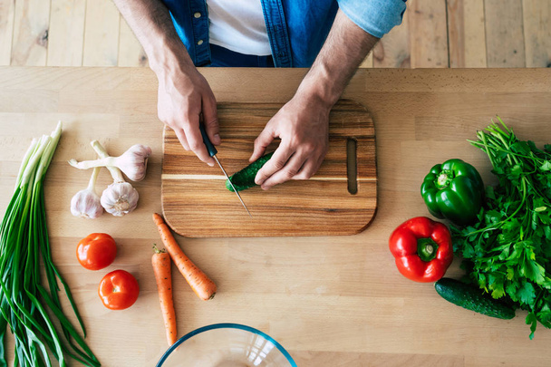 Man cooking healthy food. Fresh vegetables on the cutting board. Concept of cooking. Diet. Healthy and vegan lifestyle. Cooking at home. Prepare food. Male hands cutting vegetables in the kitchen - Foto, Bild