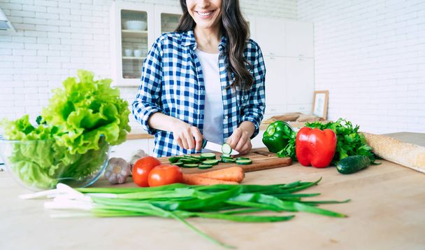 Female hands cutting vegetables in the kitchen. Woman cooking healthy food. Fresh vegetables on the cutting board. Concept of cooking. Diet. Healthy and vegan lifestyle. Cooking at home. Prepare food - 写真・画像