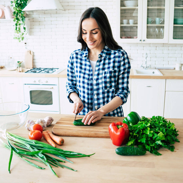 Красива молода жінка готує овочевий салат на кухні. Здорова їжа. Веганський салат. Дієта. Концепція дієти. Здоровий спосіб життя. Куховарити вдома. Приготуйте їжу. Різання інгредієнтів на столі
 - Фото, зображення