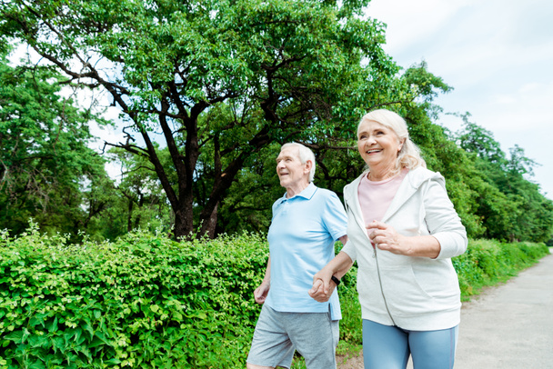 Glückliche Seniorin läuft in Park neben Ehemann  - Foto, Bild