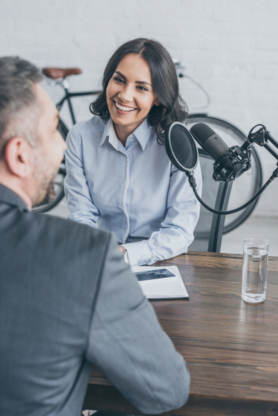 enfoque selectivo de sonriente presentador de radio entrevistando a empresario en estudio de radiodifusión
 - Foto, imagen