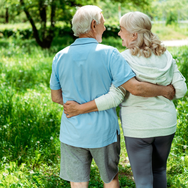 χαρούμενο συνταξιούχος άνθρωπος αγκαλιάζει ευτυχισμένη ανώτερη γυναίκα σε πράσινο πάρκο  - Φωτογραφία, εικόνα