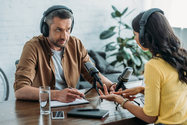 два серьезных радиоведущих разговаривают во время записи подкаста в студии вещания
 - Фото, изображение