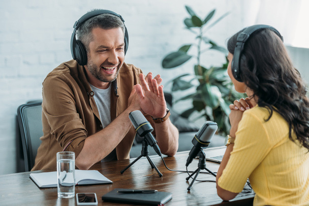 cheerful radio host showing no sign while recording podcast with colleague - Foto, Bild