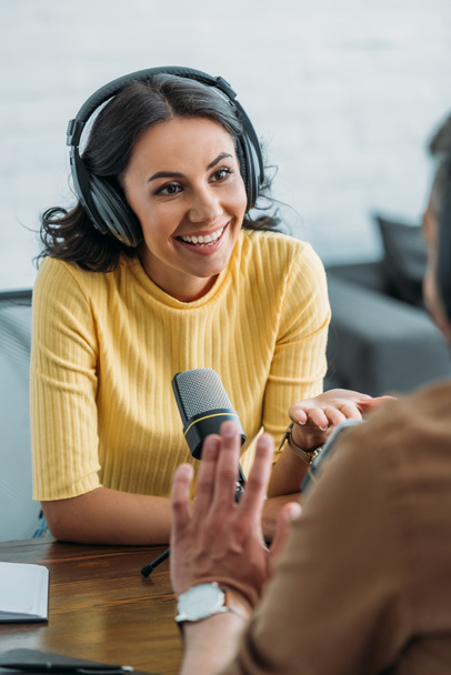 привлекательный радиоведущий, улыбающийся во время разговора с коллегой в студии вещания
 - Фото, изображение