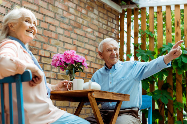 низький кут зору щасливого старшого чоловіка, вказуючи пальцем біля веселої дружини
  - Фото, зображення