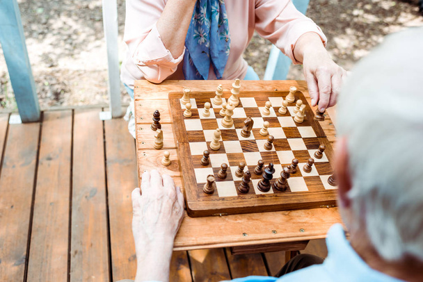 περικομμένη θέα του συνταξιούχου άντρα και της γυναίκας που παίζει σκάκι  - Φωτογραφία, εικόνα