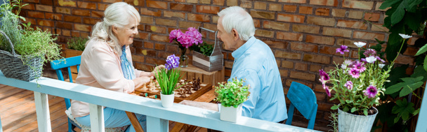 Panoramaaufnahme eines glücklichen Rentnerehepaares beim Schachspielen  - Foto, Bild