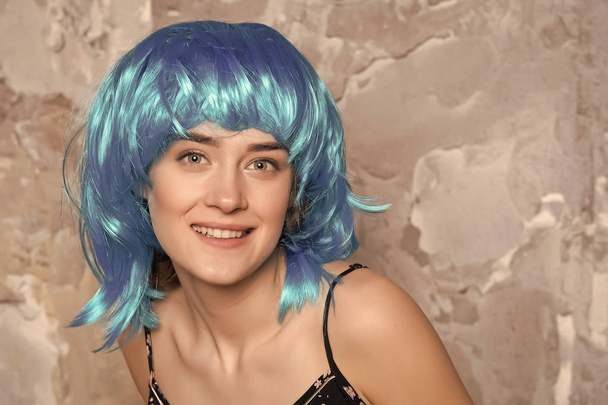 Freak concept. Lady on smiling face posing in blue wig, concrete wall background. Woman with blue hair looks unordinary and extraordinary. Lady freak with unordinary appearance - Foto, Imagen