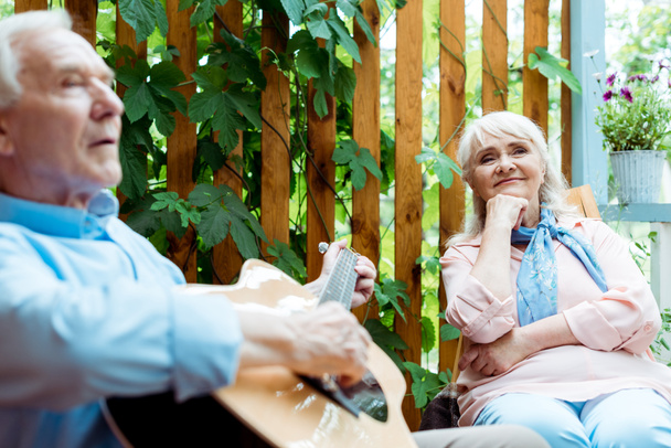 selektywne skupienie się na emerytowanym kobieta słuchania podczas gdy mąż gra gitara akustyczna  - Zdjęcie, obraz